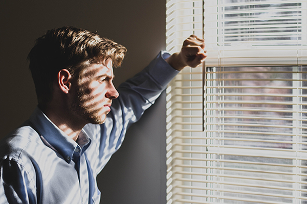 man despondently looking out the window